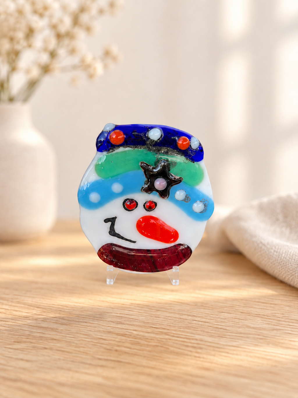 Glass snowman face with a turquoise and blue hat and colorful decorative details