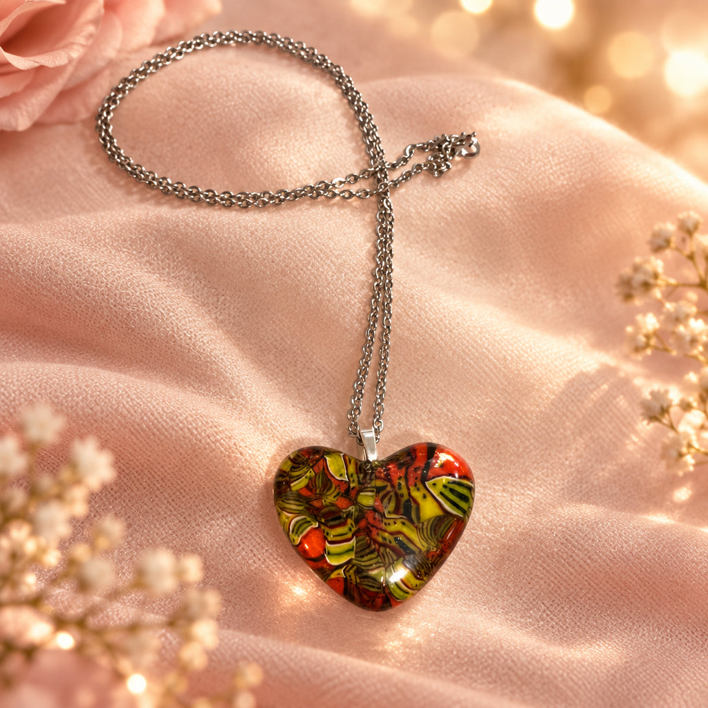 Multicolored glass heart pendant on a silver-tone chain, displayed on pink fabric