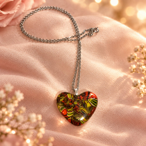 Multicolored glass heart pendant on a silver-tone chain, displayed on pink fabric
