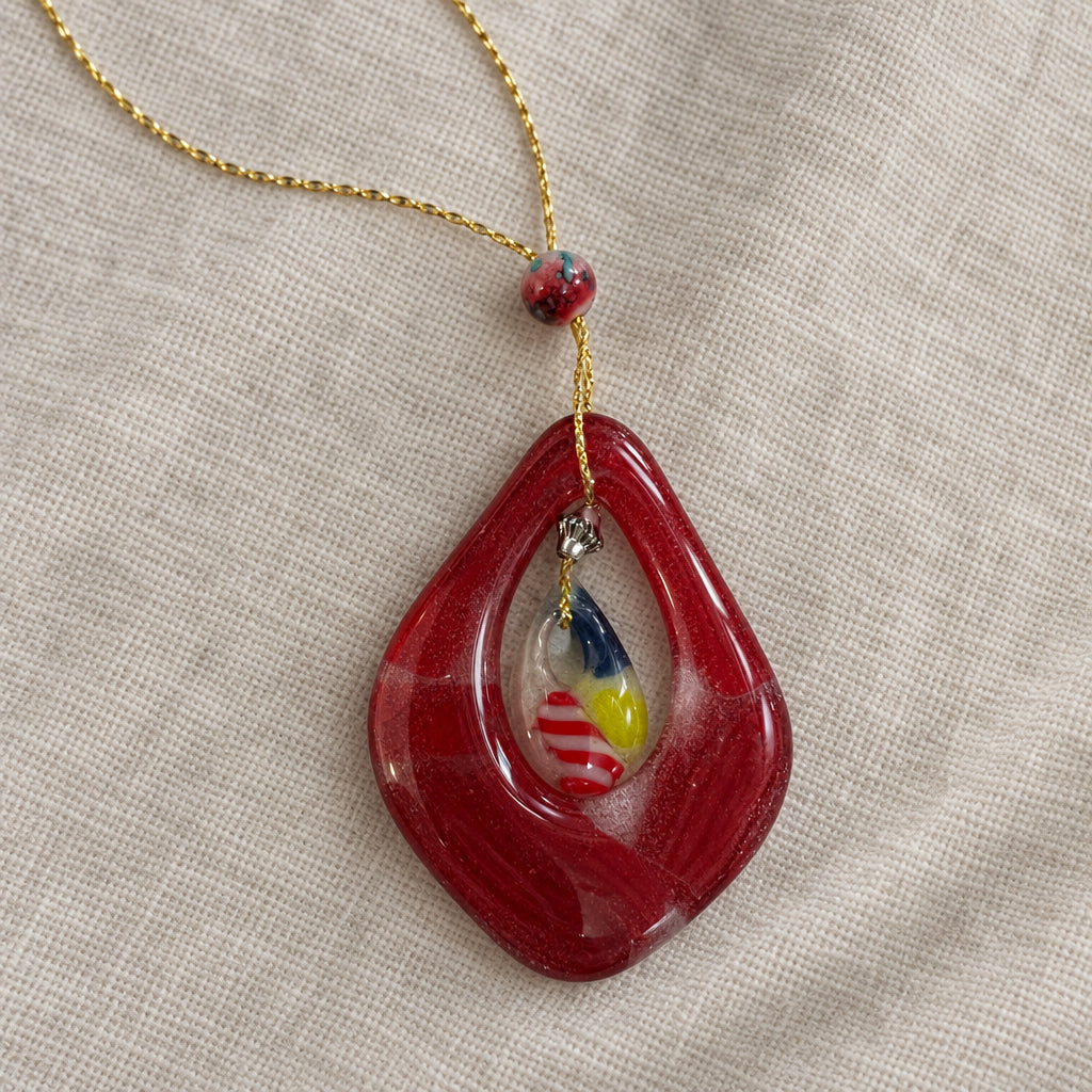 Red teardrop-shaped openwork glass pendant with a smaller colorful center on a chain