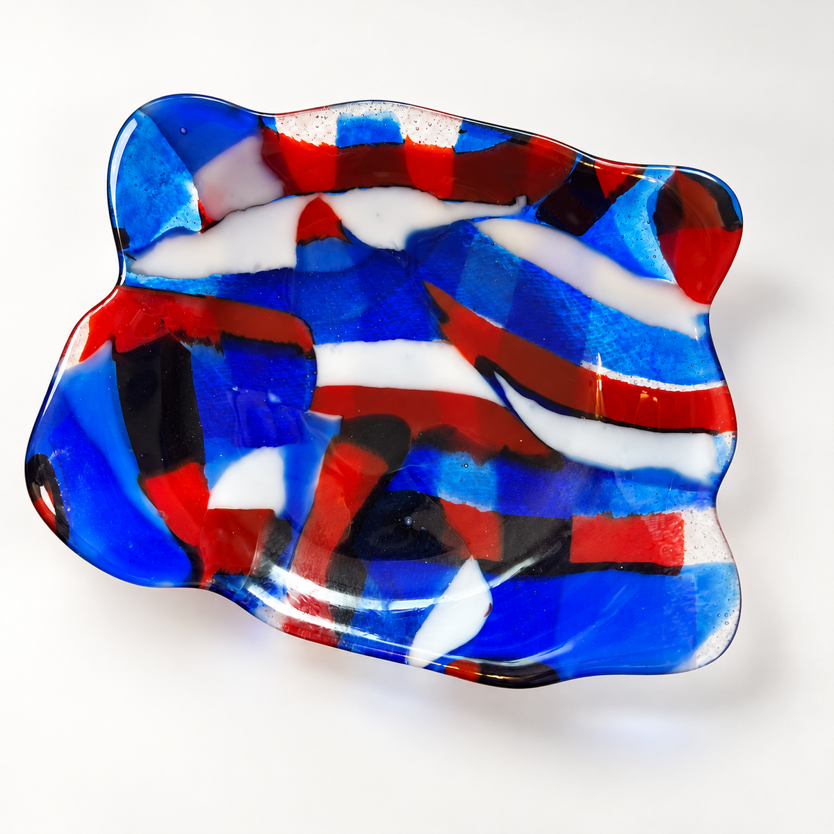 Overhead view of a red white blue and black fused glass catchall dish